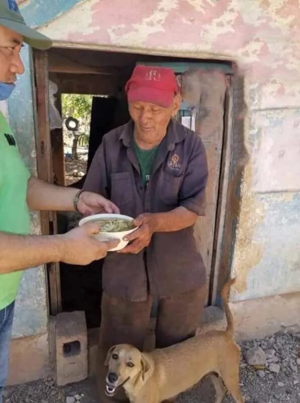 Un grand-père au grand cœur porte son chien pour qu'il ne se brûle pas les pattes sur l'asphalte